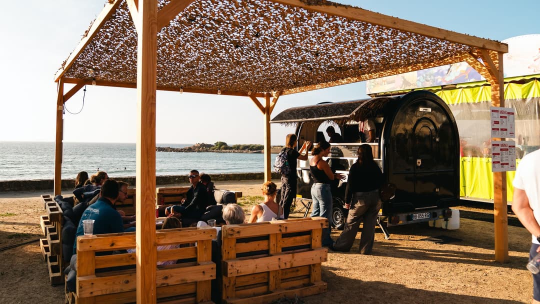 Food truck trailer by the beach, customers seated under the pergola
