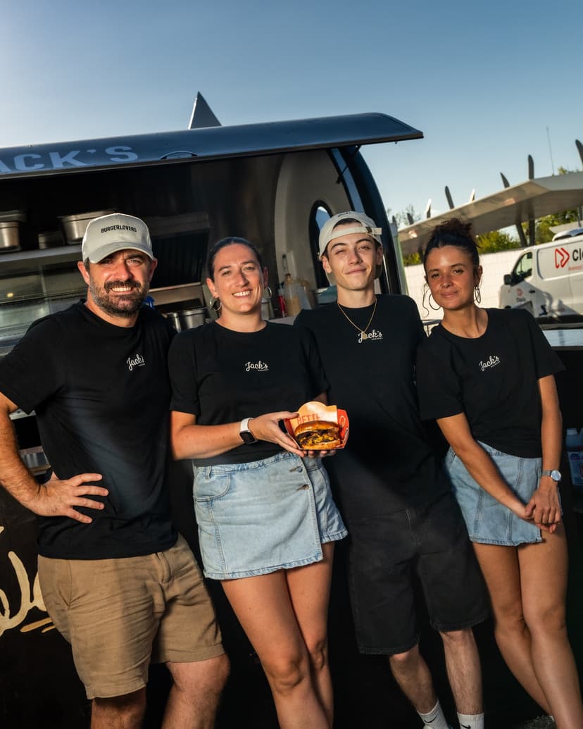 Das Team von Jack’s Burger vor seinem Food-Truck-Anhänger, einen Burger in der Hand