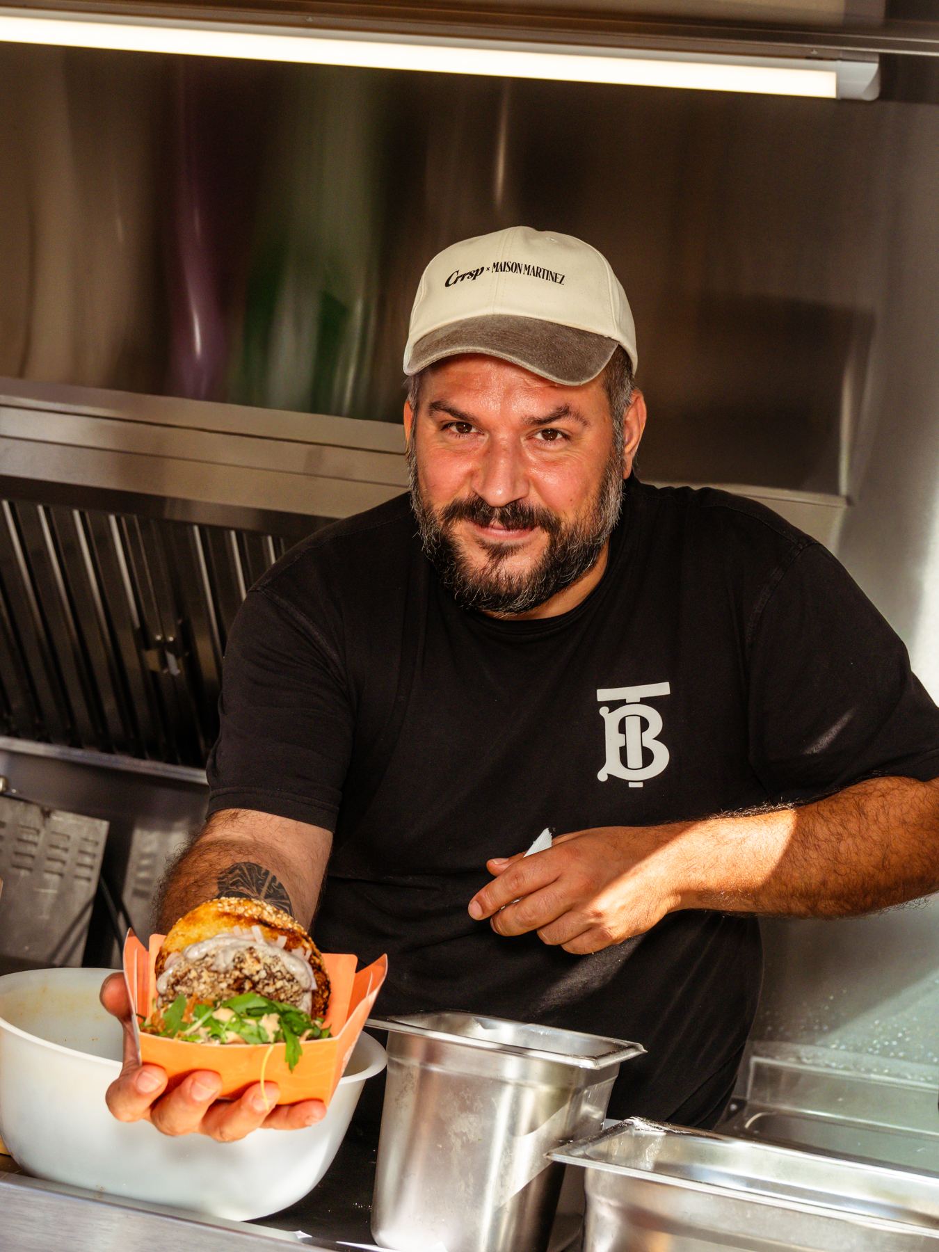 Un chef souriant devant la hotte de sa remorque food truck